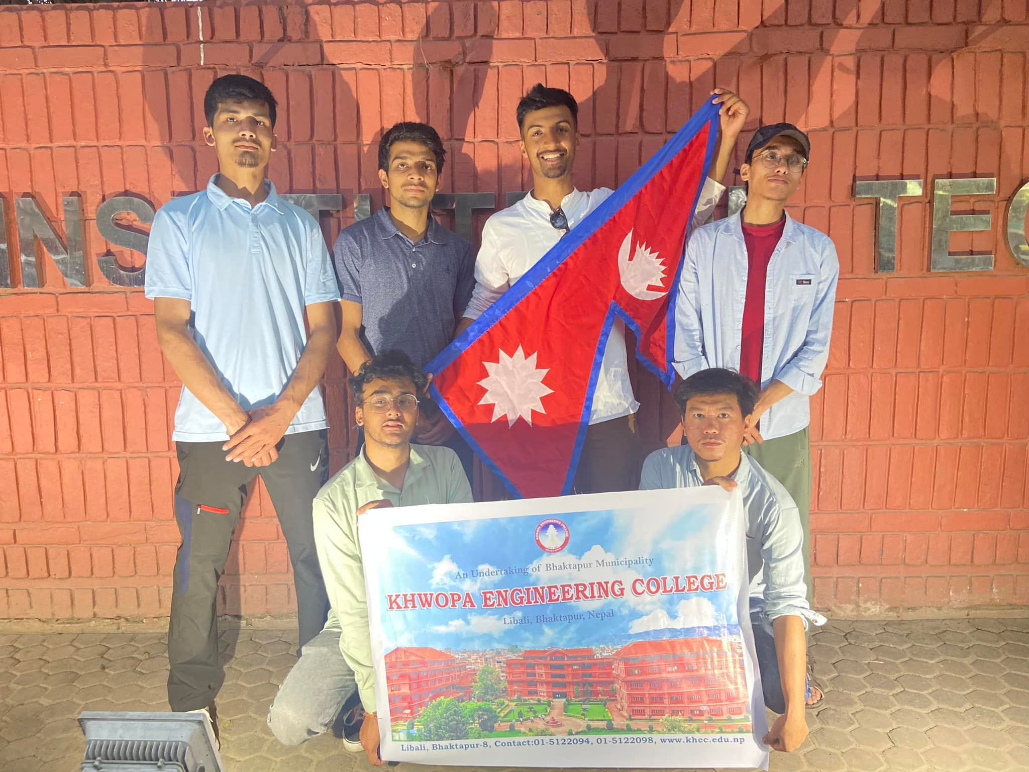 Subarna Poudel with six classmates outside Khwopa Engineering College, holding the flag of Nepal and a college banner.